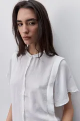 Camisa negra de manga corta, con cuello mao y cierre frontal de botones, de silueta amplia y tejido liviano con textura sutil.