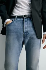 Jeans de mezclilla rígida de algodón, color azul claro con efecto lavado y ligero desgaste. De tiro medio, corte recto desde la cadera hasta la rodilla y ligeramente acampanado en el bajo (bootcut). Cierre frontal con botonadura y cinco bolsillos.