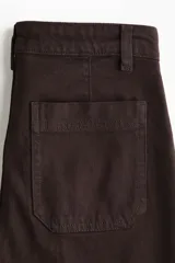 Pantalón jean de tiro alto en color marrón, de corte amplio y relajado, con bolsillos delanteros de parche y raya marcada al frente.