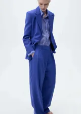 Pantalon de vestir color azul, de corte wide leg y tiro alto. Presenta pinzas delanteras, bolsillos laterales y cierre frontal con botón y cremallera oculta.