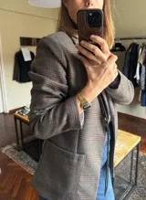 Blazer femenino forrado de corte tradicional, levemente entallado en la cintura, con mini hombreras. Presenta un diseño de cuadros, botón metálico con escudo y costuras en tono contraste.