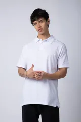 Chomba de manga corta en color blanco, con cuello clásico y cierre frontal de dos botones. Presenta un corte recto y diseño minimalista.