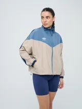 Campera cortaventos Umbro de diseño colorblock en tonos celeste, beige y azul marino, con cuello alto, cierre frontal y bolsillos laterales.