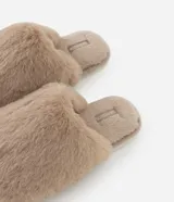 Pantufla cerrada de peluche color beige, con suela plana y diseño cómodo para el hogar.