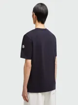 Remera Moncler de algodón color azul oscuro, con cuello redondo, manga corta y gran estampado gráfico frontal con el nombre de la marca en tonos blanco y rojo.