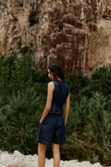 Shorts de denim azul oscuro, tiro alto, con pinzas delanteras y corte ancho. Incluye un cinturón fino marrón con hebilla de eslabones dorados.