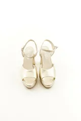 Sandalias de taco grueso y plataforma delantera, confeccionadas en cuero vacuno color dorado con tira en la parte frontal y correa ajustable al tobillo.