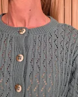 Cardigan de punto color tostado, de manga corta y cuello redondo, con cierre frontal de botones y diseño texturizado.