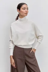 Sweater de punto color negro, con cuello alto y mangas largas de corte raglán.