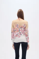 Sweater de punto con estampado floral en tonos rosados y marrones sobre base color crema, de cuello redondo y manga larga.