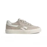 Championes deportivos Reebok de mujer, color beige claro con detalles en blanco. Diseño de caña baja con capellada de lona y suela de goma vulcanizada. Presenta el logo Reebok en el lateral y un detalle de marca en el talón.