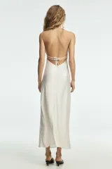 Vestido largo de satén color blanco, con cuello halter y escote en pico, de corte recto y fluido.