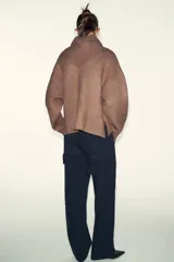 Jersey de punto color marrón, con cuello redondo y detalle de pañuelo integrado a tono. Presenta manga larga y diseño con aberturas laterales en el bajo.