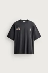 Camiseta boxy fit de color gris oscuro, con cuello redondo, manga corta y estampados contrastantes en el delantero.
