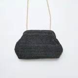 Bolso tipo clutch de estructura rígida, tejido en rafia color negro, con cierre superior y cadena metálica dorada para llevar al hombro.