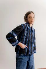 Saco tejido a mano en crochet con diseño de rayas verticales, manga larga y cuello camisero. Presenta cierre frontal con botones y bolsillos delanteros aplicados.