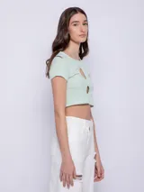 Top corto de manga corta color amarillo con estampado de lunares blancos y aberturas circulares en el escote.