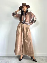 Pantalón tipo palazzo de corte oversized, confeccionado en tela con textura aterciopelada en color negro. Presenta cintura alta con pinzas, bolsillos laterales y un cinturón ancho integrado con hebilla al tono.