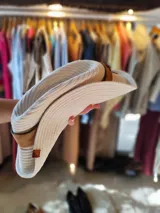 Sombrero de algodón tejido estilo fedora, color mostaza, con cinta de cuero marrón decorativa alrededor de la copa.