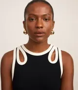 Blusa sin mangas confeccionada en rib de viscosa y elastano, color negro con ribete blanco. Posee breteles anchos con aberturas cutout en formato gotas y cuello redondo.