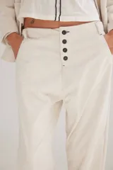 Pantalón de pana de algodón con tiro bajo y calce relajado. Presenta una botonadura frontal visible como detalle principal y diseño de estilo vintage.