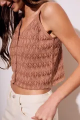 Top color marrón con textura lurex, breteles finos y cierre frontal con botones.