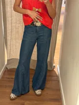 Jean de denim azul con bolsillos delanteros aplicados, costuras verticales y diseño de tablas en los laterales de las piernas amplias.