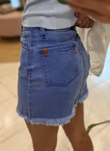 Minifalda de jean azul con botones frontales y ruedo desflecado.