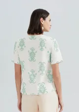 Blusa color salmón con estampado de flores blancas, de mangas cortas con volados y cuello redondo.