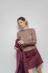 Falda corta de gamuza color bordó, con detalle de bordado geométrico vertical en el frente y bolsillo decorativo lateral.