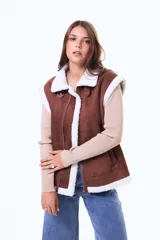 Chaleco estilo gamulán color marrón, con interior y bordes de corderito blanco. Presenta cierre frontal, cuello solapa y bolsillos laterales.