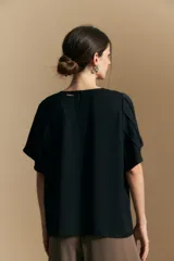 Top de color azul, con escote redondo a la base y mangas cortas amplias con caída fluida. Presenta una silueta relajada y un diseño minimalista.