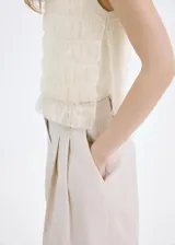Top de punto fino color beige, con diseño recto, cuello redondo, tirantes anchos y detalles fruncidos con capas semitransparentes.