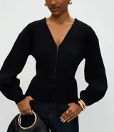 Cardigan de punto negro con escote en V, cierre frontal mediante ganchos metálicos y mangas largas con puños ajustados. Presenta un diseño entallado en la cintura con mangas ligeramente abullonadas.