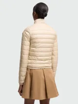 Campera corta tipo puffer de Moncler, confeccionada en nylon ligero con diseño acolchado horizontal. Presenta cuello alto, cierre frontal con cremallera, bolsillos laterales con solapa y ajuste elástico en los puños.