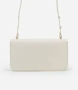 Cartera tipo shoulder bag de tamaño mediano, confeccionada en poliuretano color marrón oscuro. Presenta una solapa frontal con un detalle metálico dorado de forma orgánica y asa ajustable.