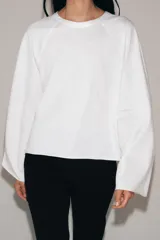 Camiseta de algodón con cuello redondo y mangas largas tipo ranglán. Presenta un corte regular y bajo recto.