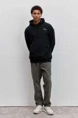 Buzo con capucha negro de corte holgado, con bolsillo frontal tipo canguro y estampa pequeña en el pecho.