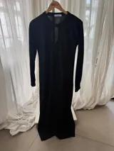 Vestido midi de morley de lana negro, con cuello redondo y abertura tipo lágrima en el pecho, de manga larga y corte ajustado.