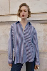 Camisa de corte clásico con cuello solapa y manga larga, confeccionada en tejido oxford con diseño de rayas verticales en azul y bordó. Presenta cierre frontal con botones y bajo con aberturas laterales.