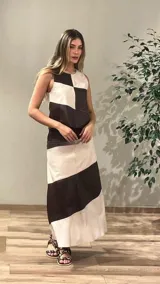 Falda larga de cuero ovino, sin mangas, con diseño de bloques de color en blanco y marrón oscuro, dispuestos en cortes diagonales y cuadrados.