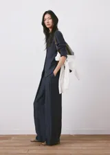 Pantalón azul marino de tiro alto con sutiles rayas diplomáticas blancas, de corte amplio y fluido con bolsillos laterales.