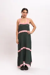 Vestido largo de punto tipo solera en color verde oscuro, con tirantes anchos y detalles de rayas horizontales en color rosado claro en el escote, la cintura, los cortes de la falda y el ruedo.