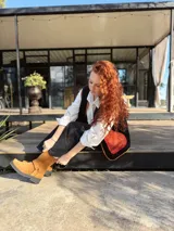 Chaleco negro con interior de corderito, con detalles en color naranja y ribeteado en marrón.