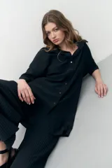 Vestido camisero negro con textura plisada, corte midi y cierre frontal con botones.