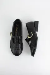 Zapato tipo guillermina estilo oxford, confeccionado en cuero negro con detalles de perforaciones decorativas en la puntera y cierre mediante tira con hebilla metálica dorada. Presenta un taco bajo cuadrado.