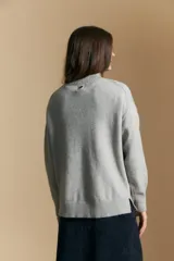 Sweater de punto color beige con diseño geométrico en relieve, cuello alto y mangas largas con puños acanalados.