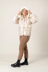 Campera puffer color crudo con brillo metalizado, con bolsillos delanteros, capucha con aplique de piel sintética desmontable y cierre frontal.
