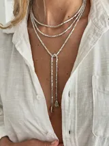 Collar estilo lariat plateado con abalorios cúbicos y dijes colgantes en los extremos.