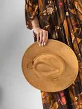 Sombrero de gamuza color tostado, estilo cowboy, con ala ancha y detalle de trenzado en la base de la copa.